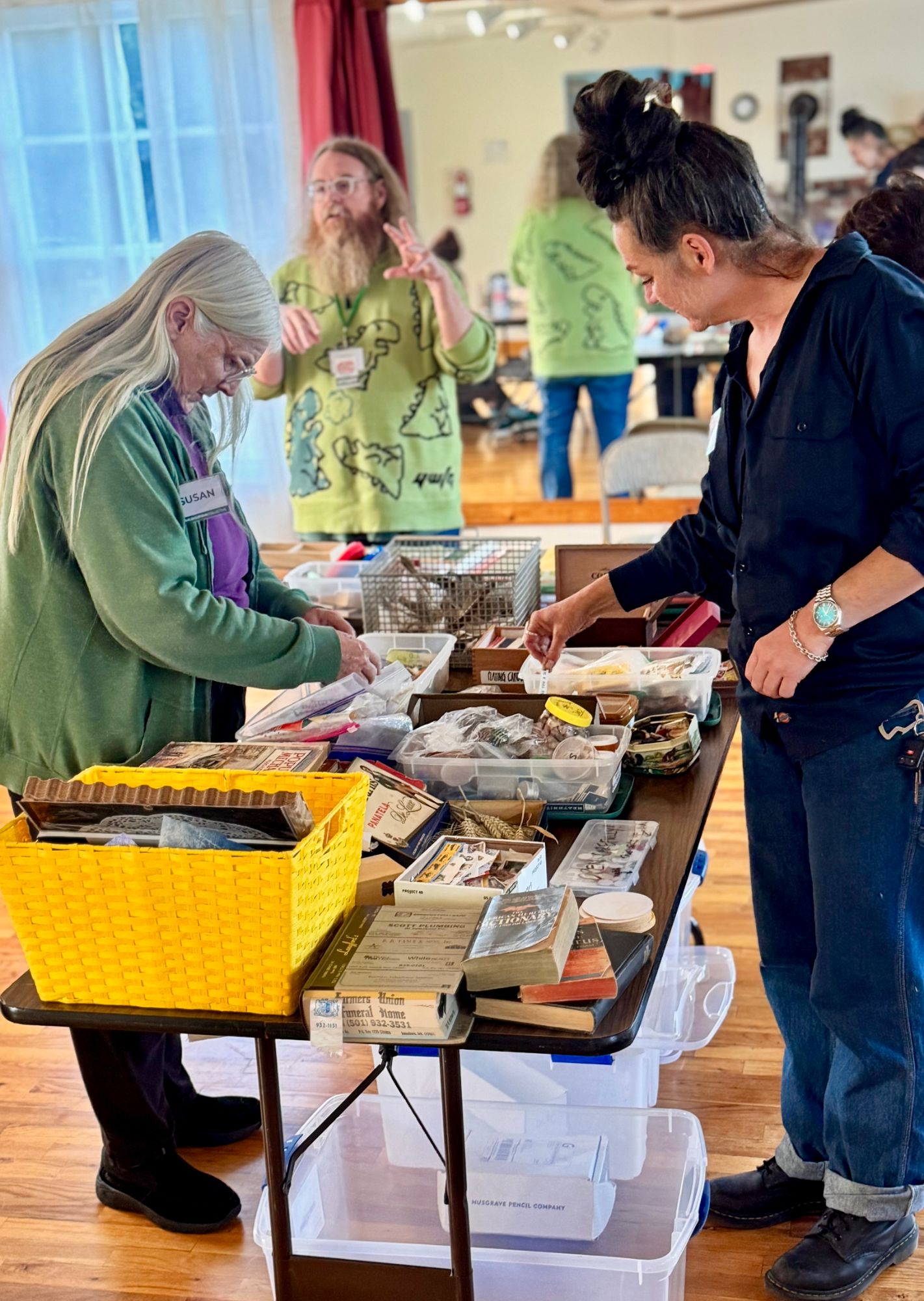 Two participants sorting through the supply table while a third person talks in the background.
